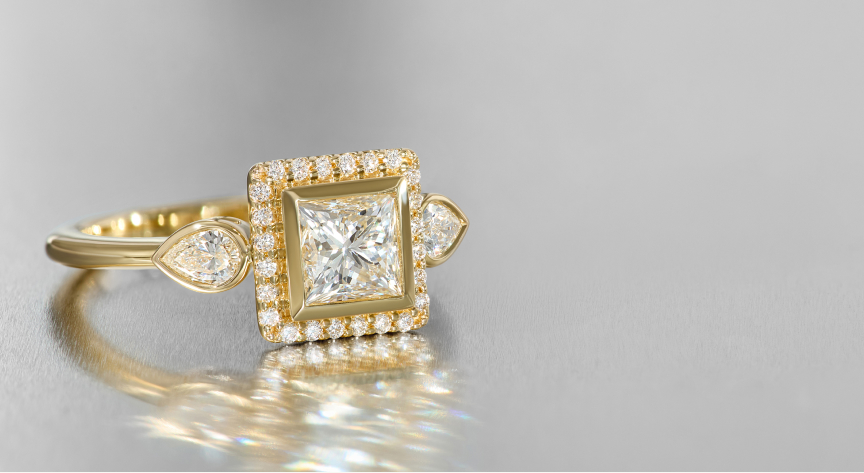 A yellow gold and diamond engagement ring casts a shadow across a greyish white table