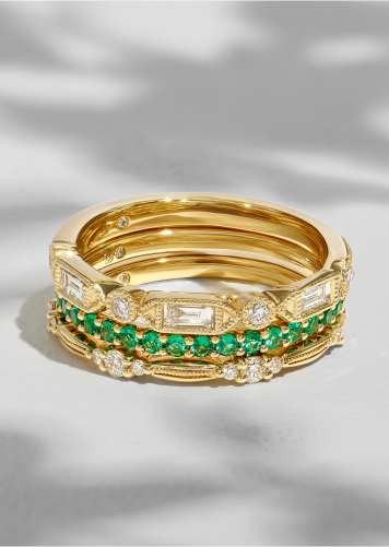 A stack of bridal bands featuring diamonds and colorful gemstones set in 14k yellow gold. 